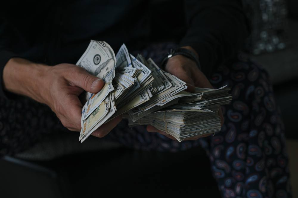 man counting large stack of money