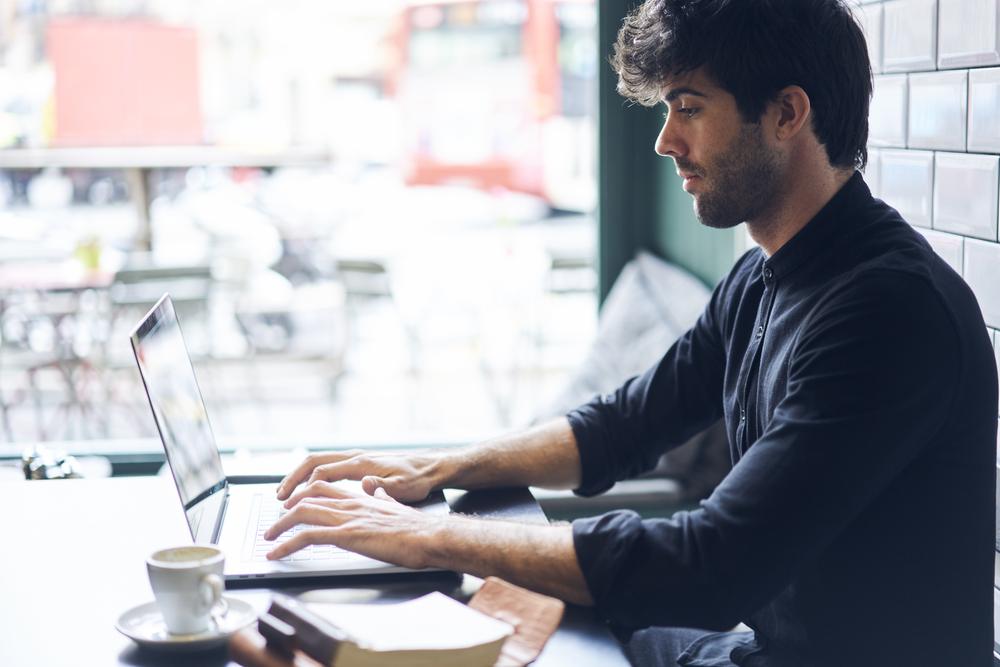 man writing a book review blog in a cafe