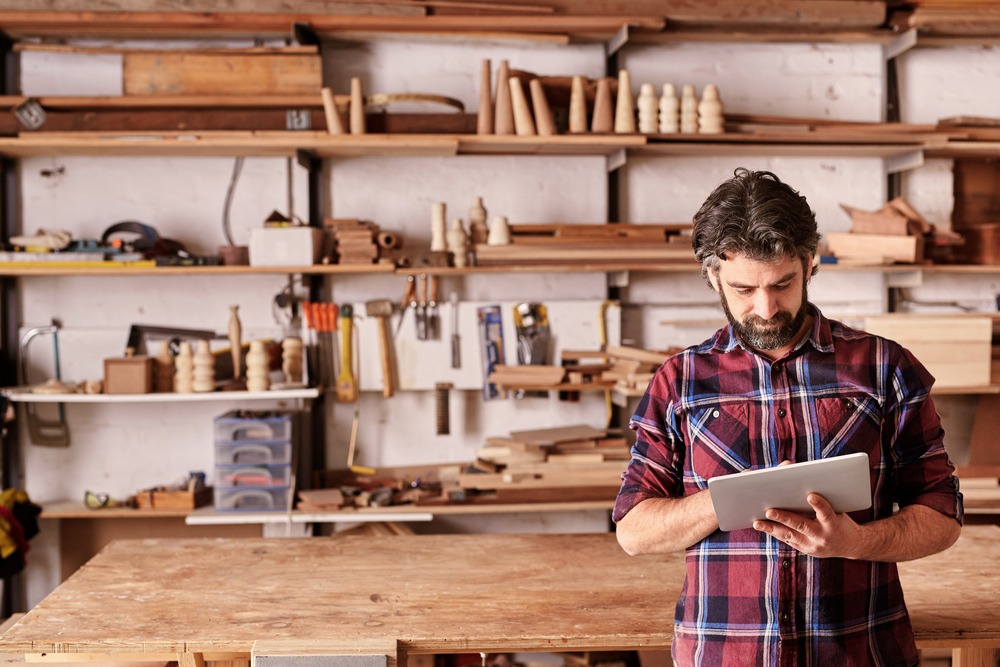 middle aged man with woodworking business and tablet for orders