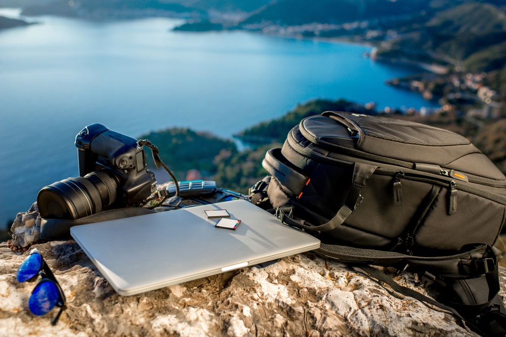 photography blogger traveling with laptop and dslr camera with zoom lens