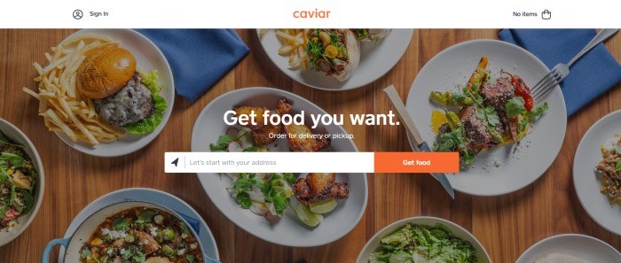 This screenshot of the home page for Caviar shows an overhead view of several plates of food on a wooden table with blue napkin, along with a search bar and white lettering reading "Get the food you want."