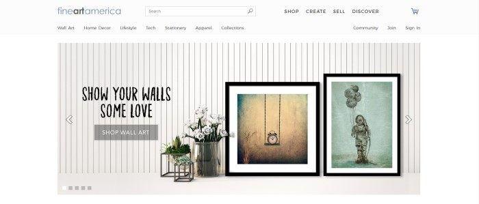 This screenshot of the home page for FineArtAmerica has a white header, navigation bar, and background behind a photo of a white wall with vertical paneling and two fine art pictures in black frames next to a large pot of white roses and two smaller green plants on plant stands, along with black text inviting customers to love their walls and a gray call to action button.