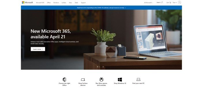 This screenshot of the home page for Microsoft has a white navigation bar with a blue bar announcing efforts to help with the COVID-19 pandemic, above a photo of an open laptop on a wooden desk with a potted plant, roll of tape, paperweight, and mobile phone, next to white text announcing the new Microsoft 365, along with a white call-to-action button.