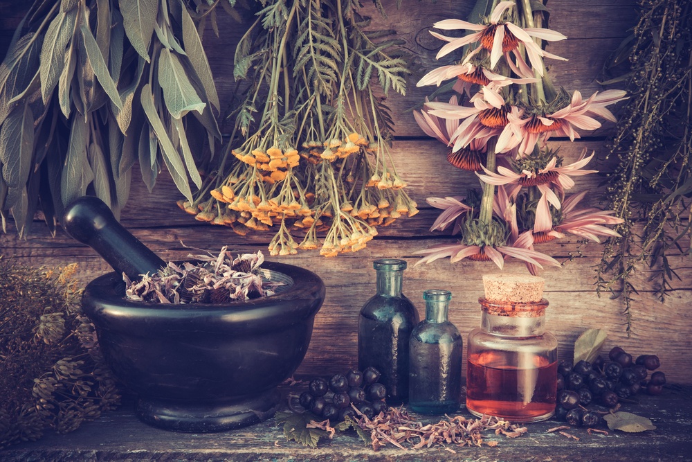 vintage essential oil bottles with medicine bowl and dried herbs and flowers