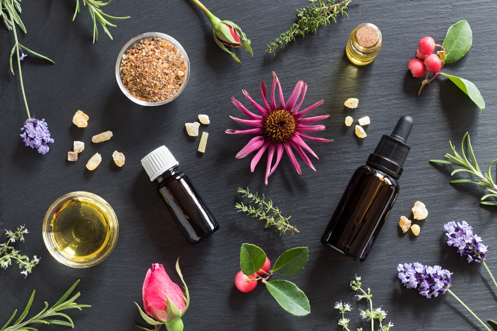 visually stunning mix of herbs, flowers, berries, and oils on black background