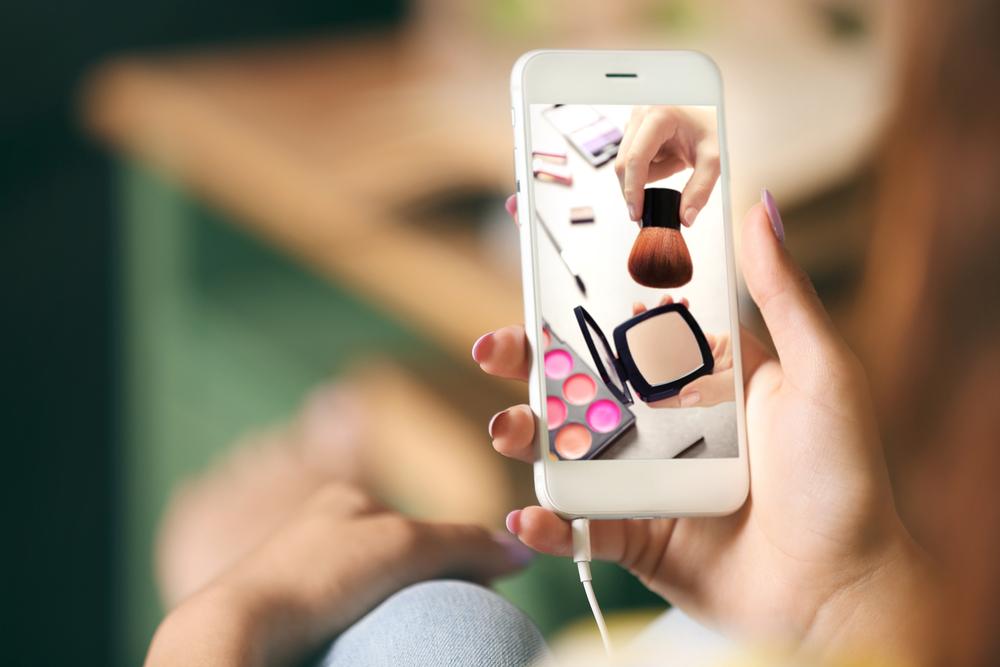 mujer que usa el teléfono para ver el tutorial de maquillaje en línea