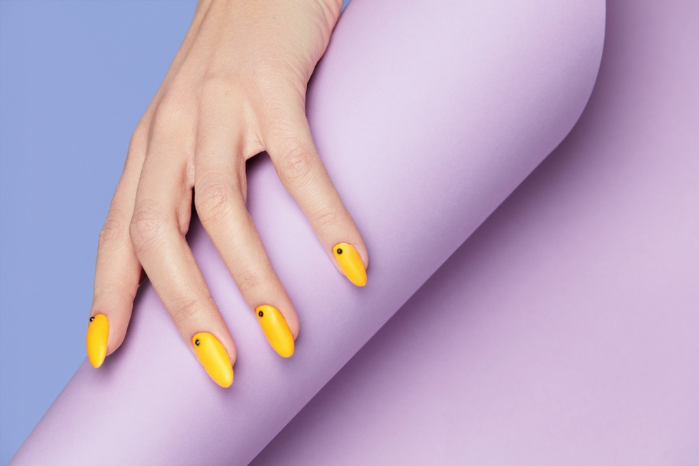 yellow designer nails with pastel purple background