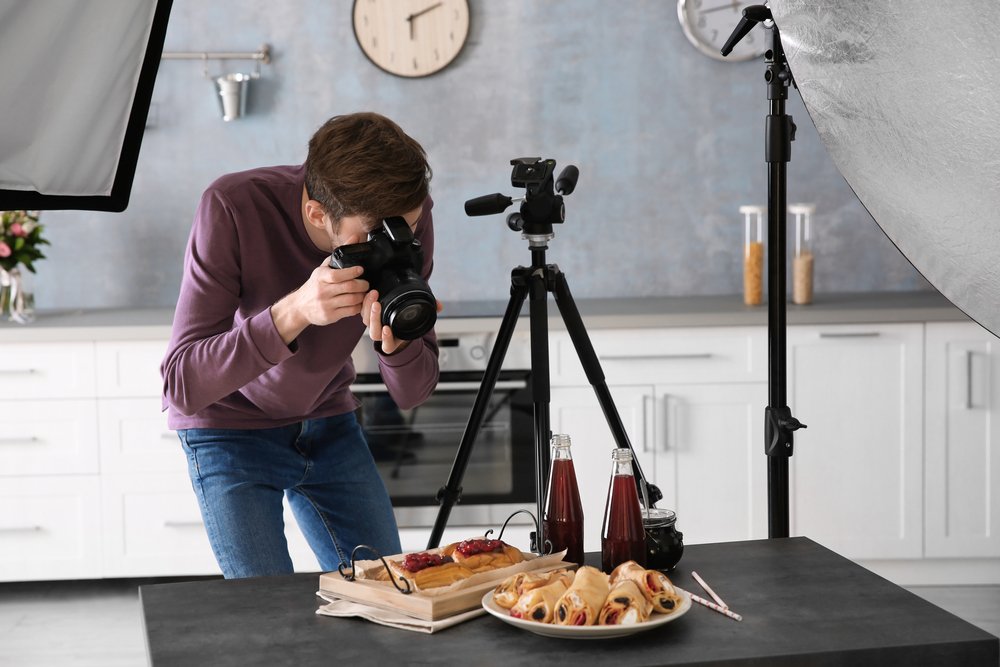 young man taking photos of dessert pastries and drinks with dslr camera