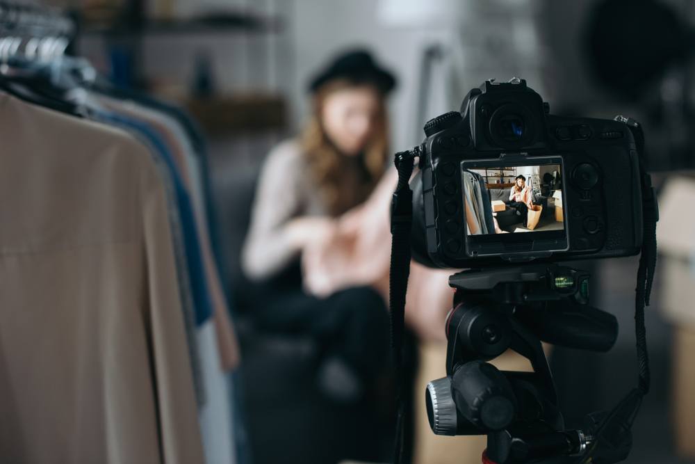 young woman in closet with dslr camera shooting fashion blog