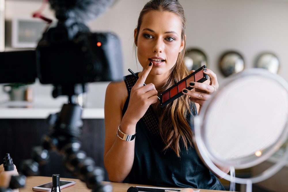 young woman recording beauty tutorial video for youtube with DSLR camera