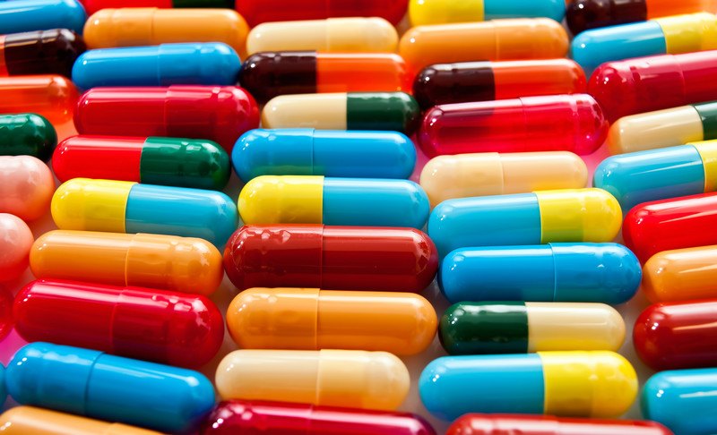 This photo is a closeup of several types of capsules in red, blue, orange, yellow, and green, representing the best pharma affiliate programs.