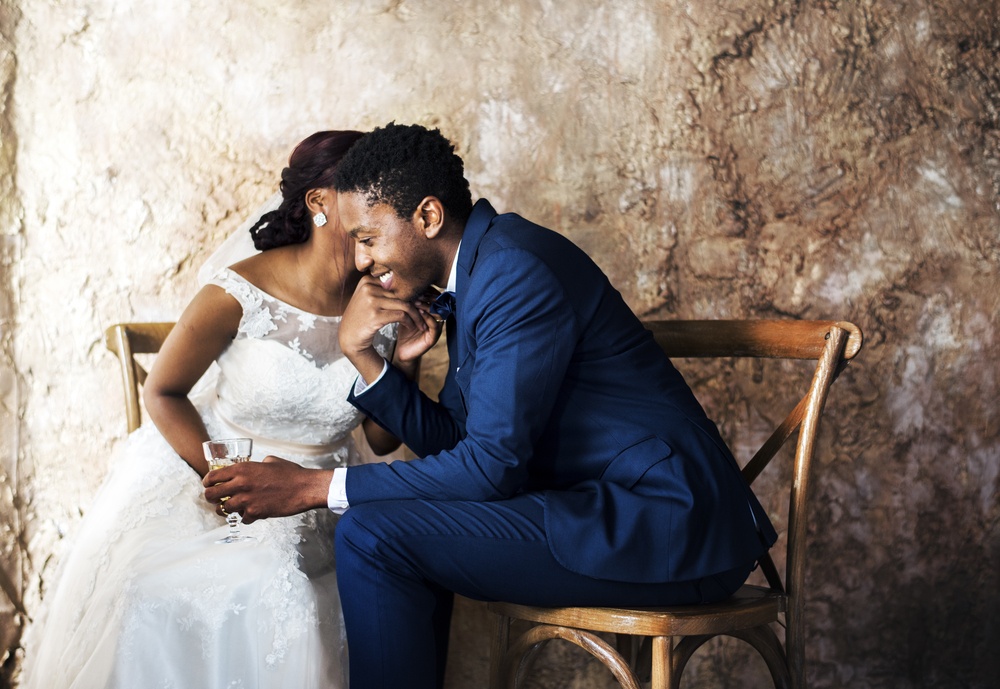 groom in blue suit with bride whisperingin his hear