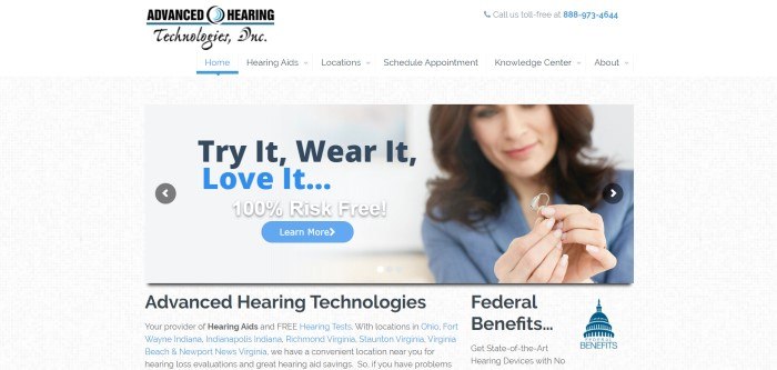 This screenshot of the home page for Advanced Hearing has a white header and navigation bar above a gray background and a photo of a dark-haired smiling woman in a light blue business suit holding a hearing aid, along with black, blue, and white text and a blue call to action button.