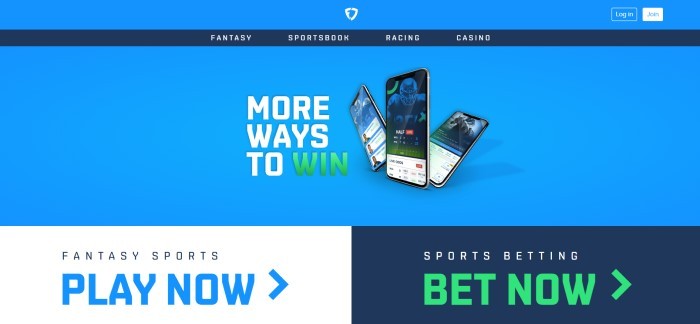 This screenshot of the home page with a blue background, a dark blue navigation bar with white text, a photo of three mobile devices with the app on the screens, with white and green text announcing more ways to win, above a white section with black and blue text on the left announcing fantasy sports and a black section announcing sports betting on the right side of the page with white and green text.