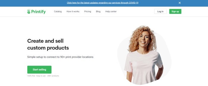 This screenshot of the home page for Printify has a blue announcement bar, a white navigation bar with a green logo and call to action button, and a white main section with a photo of a smiling blonde woman in a plain beige tee shirt on the right side of the page and a text section with black text on the left side of the page, as well as a green call to action button.