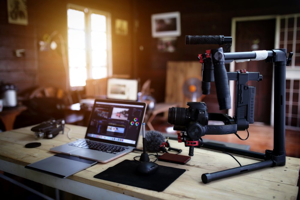 youtube vlogger equipment and hardware including laptop, mic stand, camera stand, and video editing software