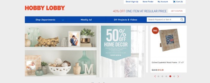 This screenshot of the home page for Hobby Lobby has a gray background, red logo, blue navigation bar, and a main section with a photo showing white shelves full of knick-knacks, along with white text announcing 50% off home décor.