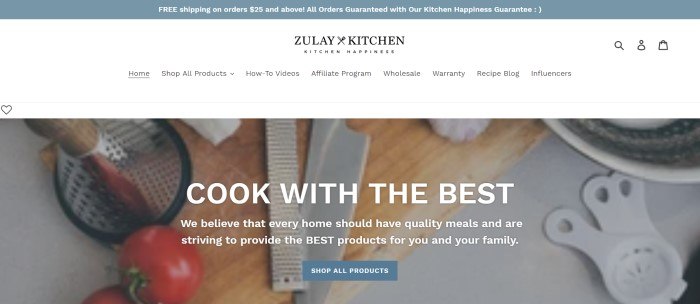 This screenshot of the home page of Zulay Kitchen has a gray header above a white navigation bar and an overhead photo of a cutting board and knife, along with white text and a gray call to action button.