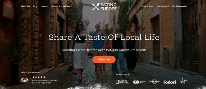 This screenshot of the home page for Eating Europe has a transparent navigation bar with white text overlaying a large photo of a group of travelers walking down a narrow European street behind white text and an orange call to action button.