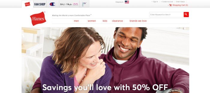 This screenshot of the home page for Hanes has a white background, red text in the navigation bar, a header showing logos of sister brands, and a photo of a smiling dark-skinned man in a maroon hoodie snuggling with a smiling brunette woman with pale skin in a purple knit jacket and pink shirt, along with white text announcing a 50% discount.