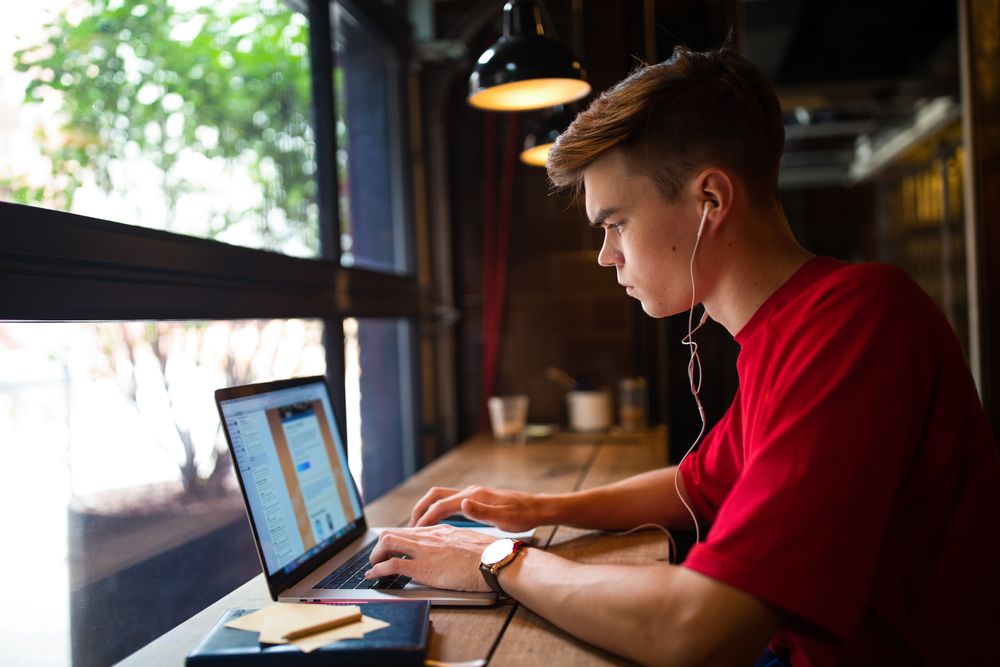 young man at cafe doing online virtual assistant work