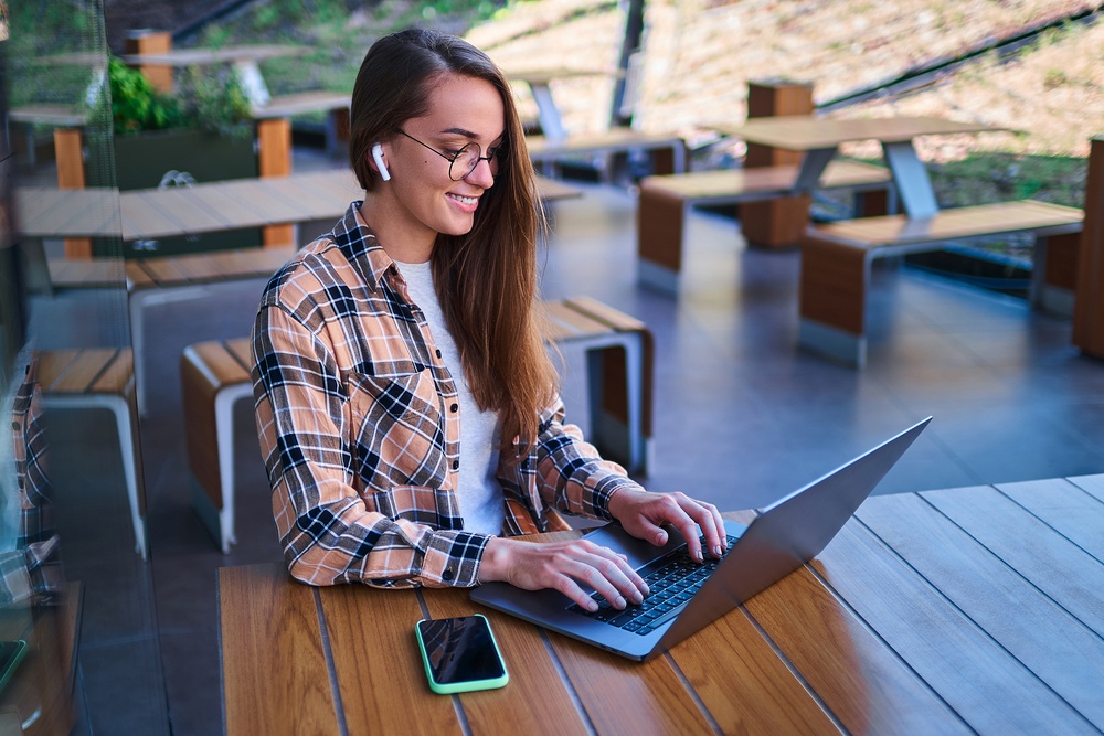 young woman sitting at cafe with earbuds listening to audio for transcription services