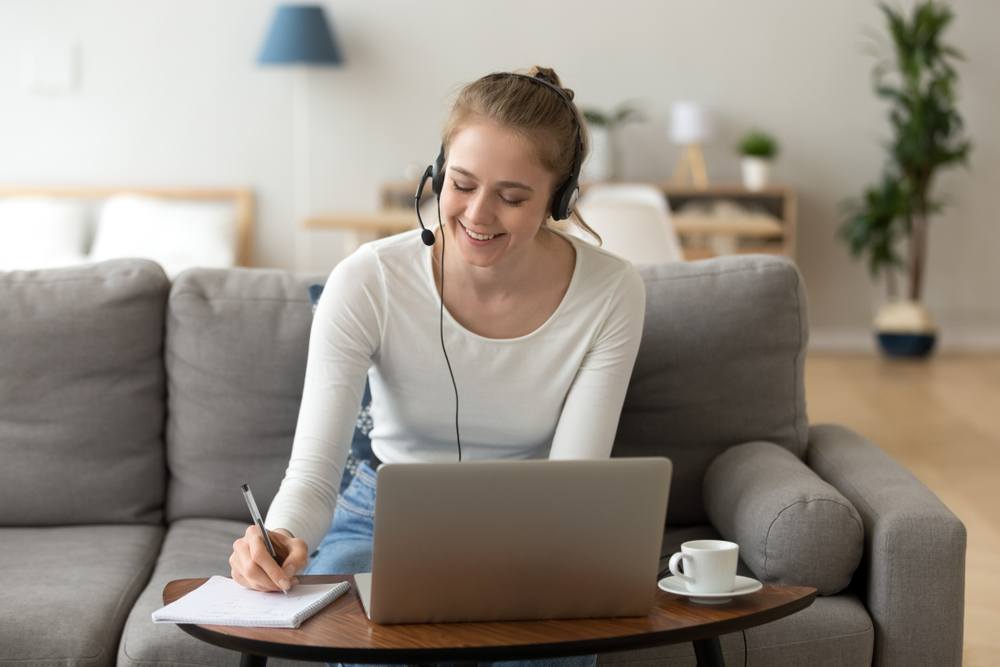 young woman teaching English online with headset and laptop