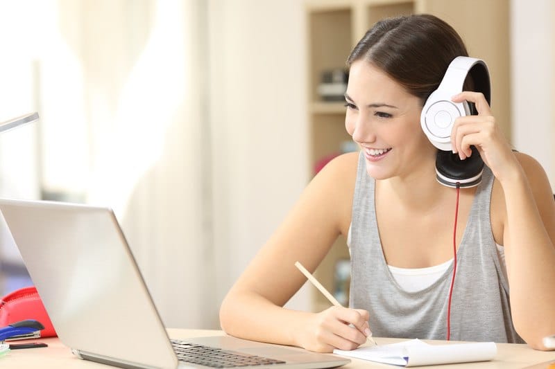 woman in casual clothes working at home with her laptop and headset