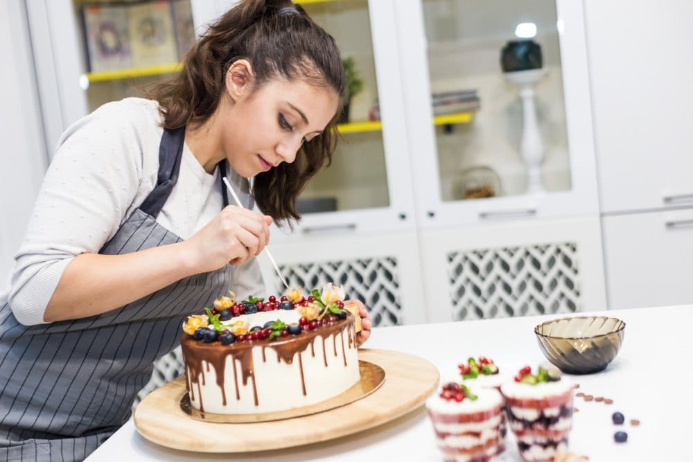 professional cake decorator putting finishing touches on cake