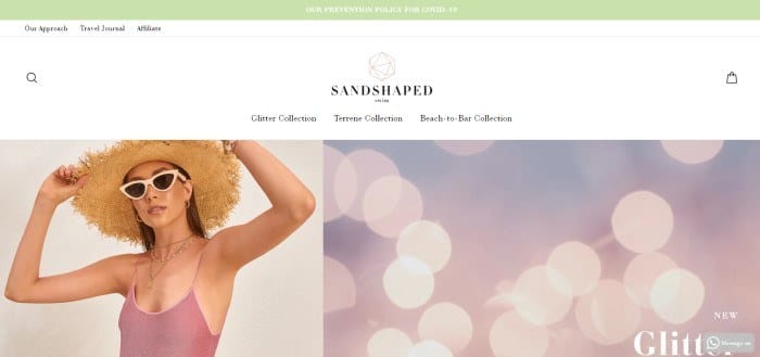 This screenshot of the home page for Sandshaped has a green header, a white navigation bar, and a set of side by side photos, with a woman in sunglasses, a straw hat, and a pink one-piece swimsuit on the left side of the page and a photo of what appears to be blurry lights in pink and purple on the right side of the page.