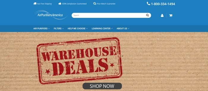 This screenshot of the home page for Air Purifiers America has a blue header and navigation bar with white text above a closeup photo of a piece of corrugated cardboard with a red stamped announcement for warehouse deals on it, along with a black call to action button.