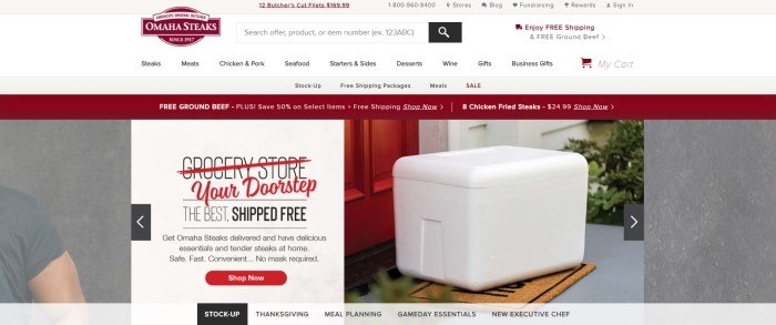 This screenshot of the home page for Omaha Steaks has a gray and white header with a burgundy logo and black text in the navigation bar, along with a burgundy announcement bar above two large photos showing the shoulder of a man in a gray tee shirt on the left side of the page and a white box of food on the stairs near a red door on the right side of the page, behind a white text box with black and red text and a red call to action button.