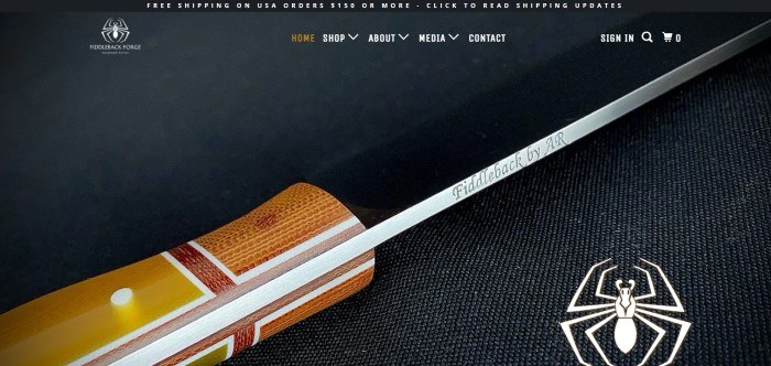 This screenshot of the home page for Fiddleback Forge has a black header, white and gold text in a transparent navigation bar, and a closeup of a Fiddleback Forge knife against a dark background, with a white spider-shaped logo in both the upper left and lower right corners of the page.