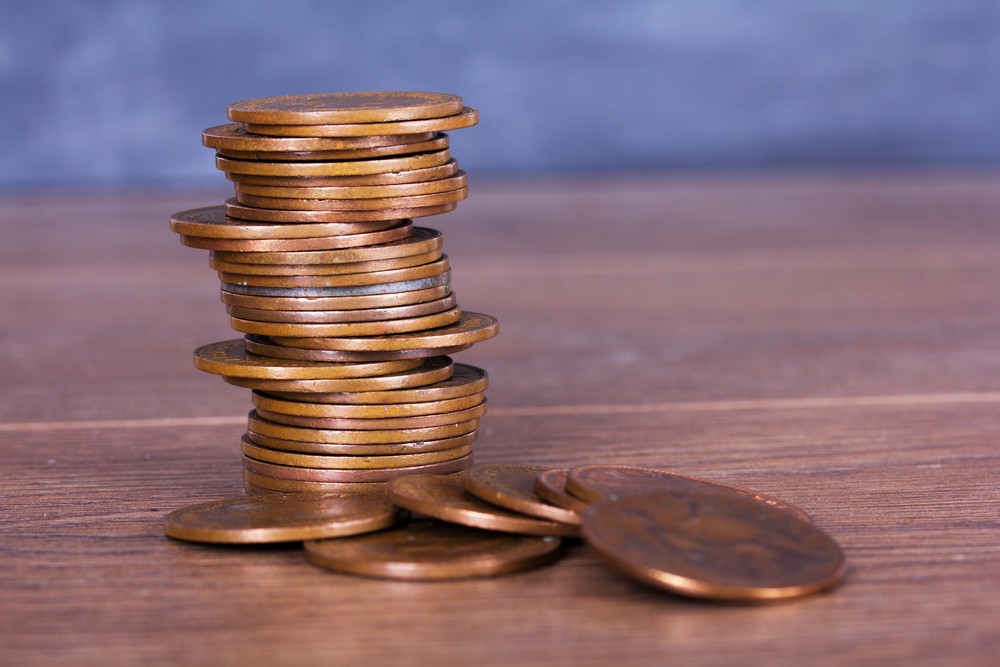 stack of pennies on table with some pennies scattered