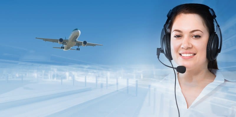 This photo shows a blue sky with an airplane flying on the left and a smiling dark-haired woman in a headset on the right, representing the question, do dispatchers make good money?