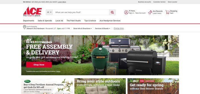 This screenshot of the home page for Ace Hardware has a gray header, a white navigation and search bar with black and red text, a white announcement bar, and a photo showing several types of barbecue grills in a green back yard, along with white text and a red call to action button.