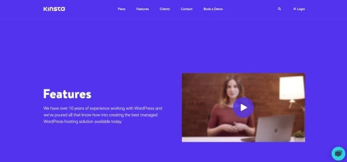 This screenshot of the home page for Kinsta has a royal blue background and header with white text, as well as a video clip on the right side of the page showing a still shot of a woman in a red shirt sitting at a table near an open laptop.