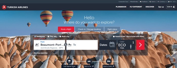 This screenshot of the home page for Turkish Airlines has a black header and navigation bar above a photo of several hot air balloons in yellow, red, blue, and pink floating above snow-covered desert mountains, behind a dark-filtered search section with a white search bar and a secondary navigation bar with one red tab.