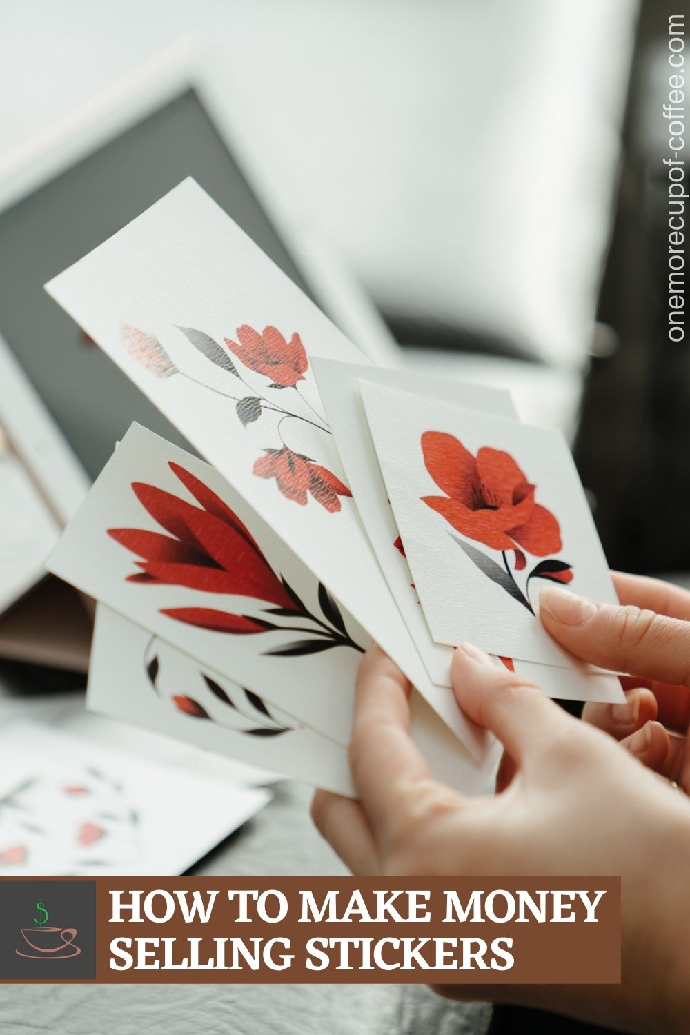 closeup image of hands holding stickers of different kind of red flowers, with a blurry background of more stickers on the table and a tablet; with text overlay on a brown banner "How To Make Money Selling Stickers"