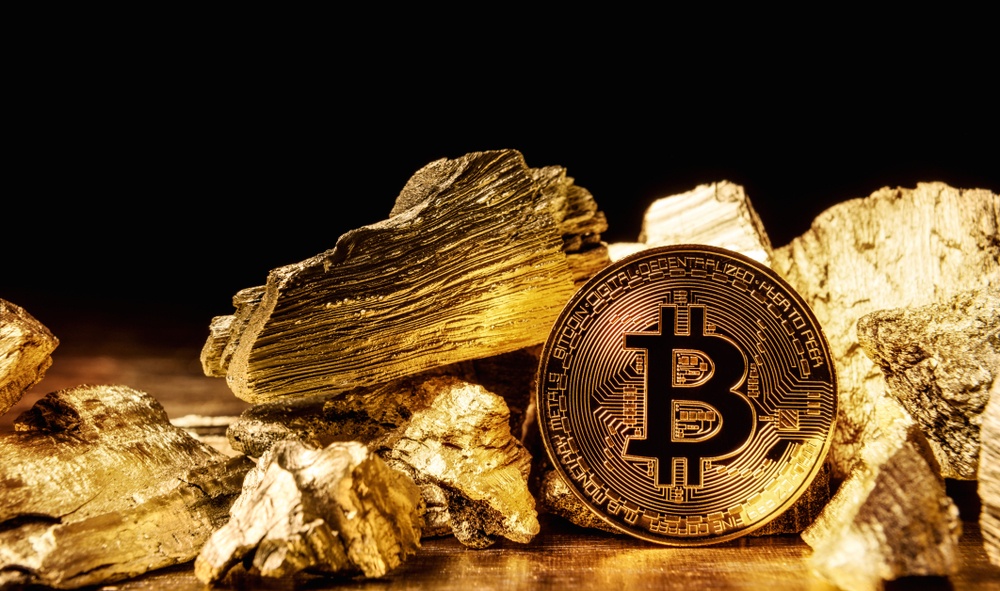 chunks of gold scattered on gold surface with bitcoin standing nearby drawing the comparison between bitcoin and gold