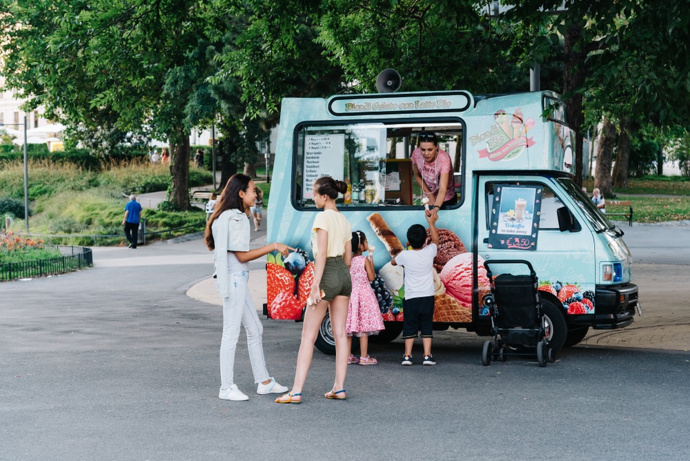 modern ice cream truck in mini van serving kids at park