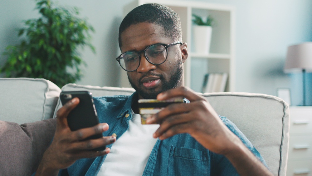 A man looks at his credit card and his phone. 