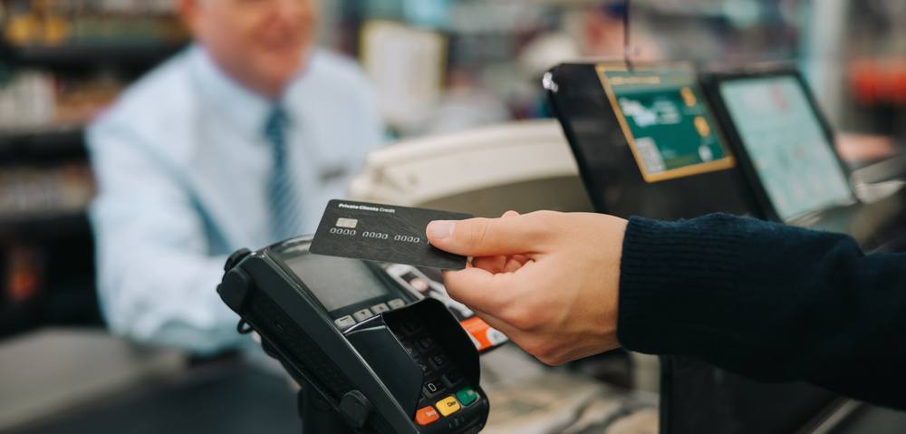 Someone holds a credit card next to a scanner. 