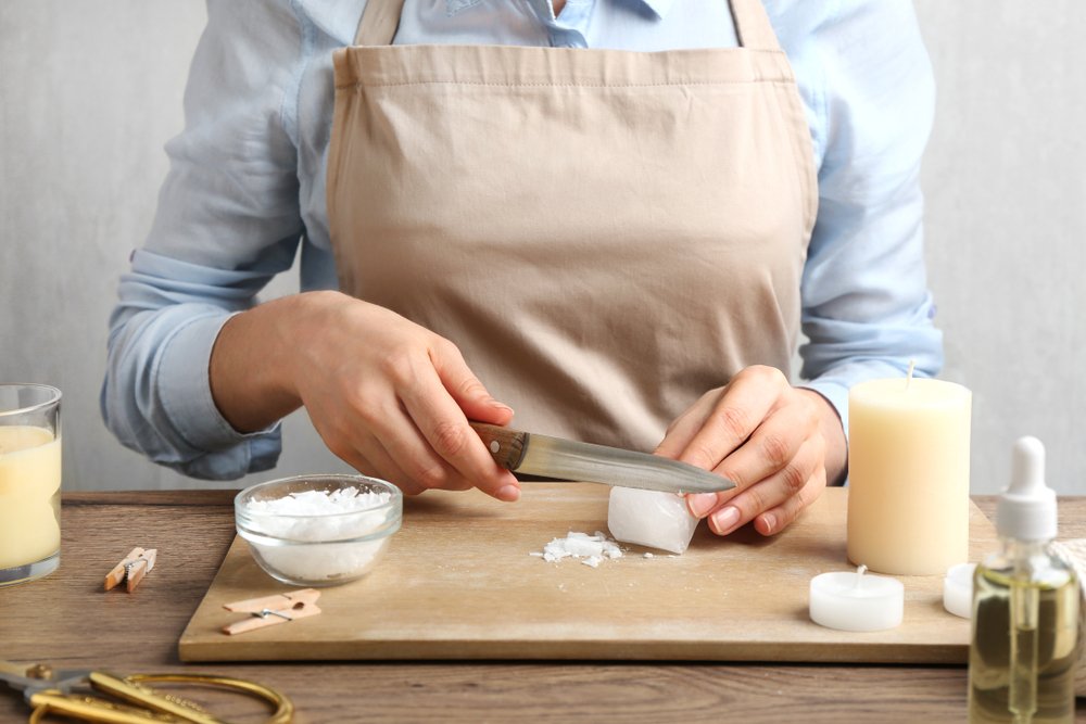 A person is cutting wax with a knife for use in a candle.