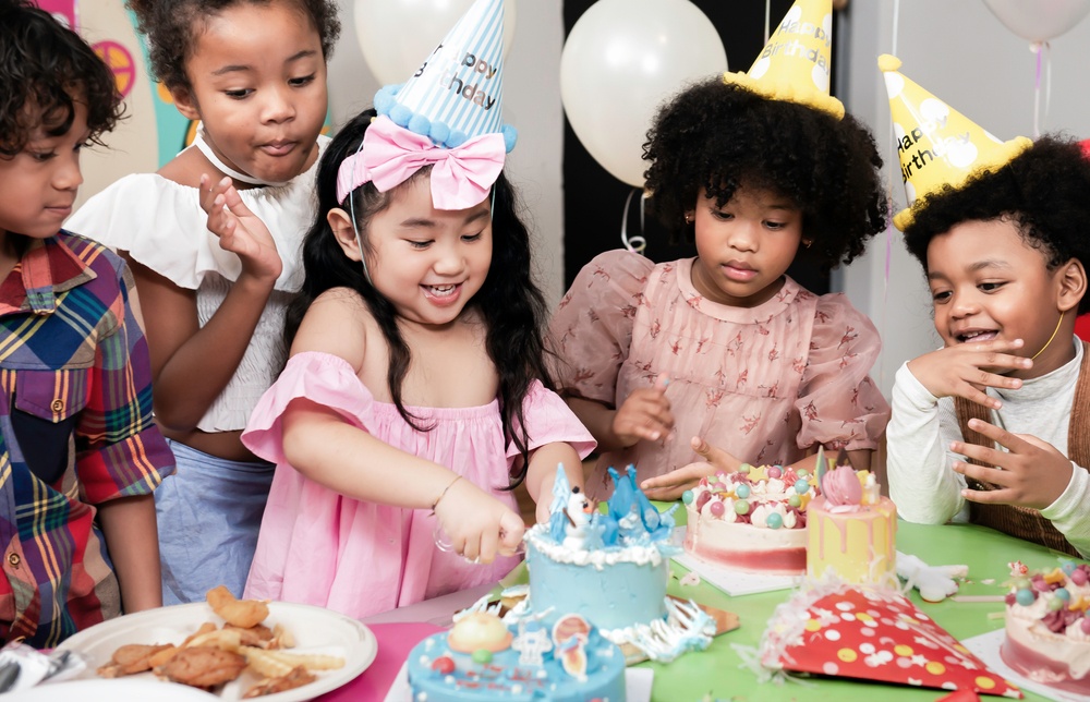 A child at a birthday party cuts a small cake.