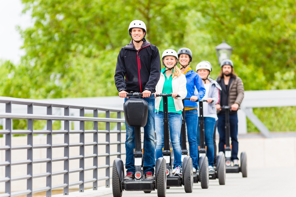 A tour guide on a segway leads a group of tourists, who are also on segways.
