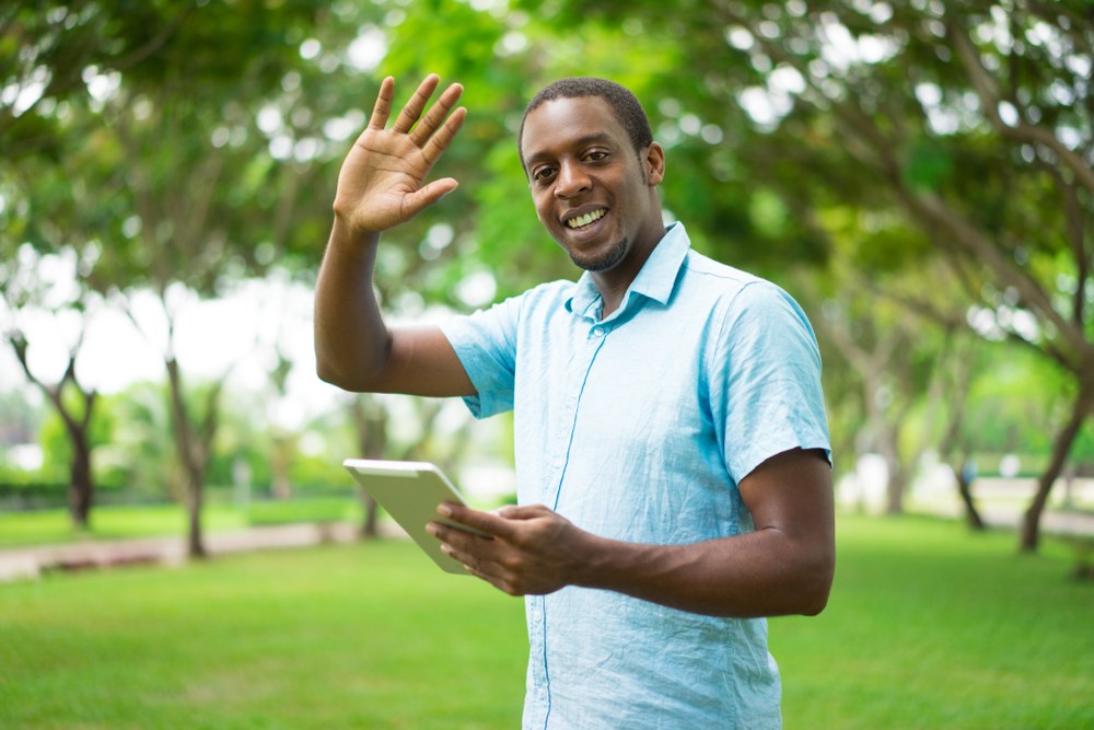 A tour guide in a garden waves and smiles.