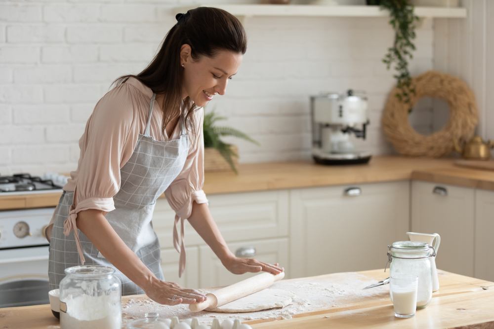 A woman uses a rolling pin to flatten dough. 