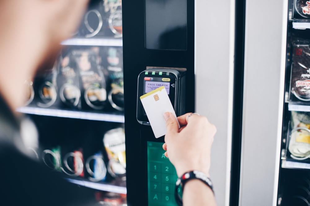 A person uses a keycard at a vending machine.
