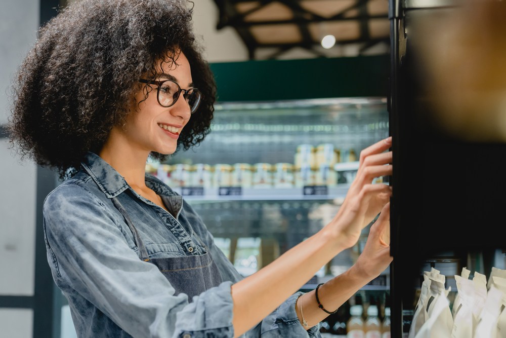 A smiling woman chooses a vending machine item.